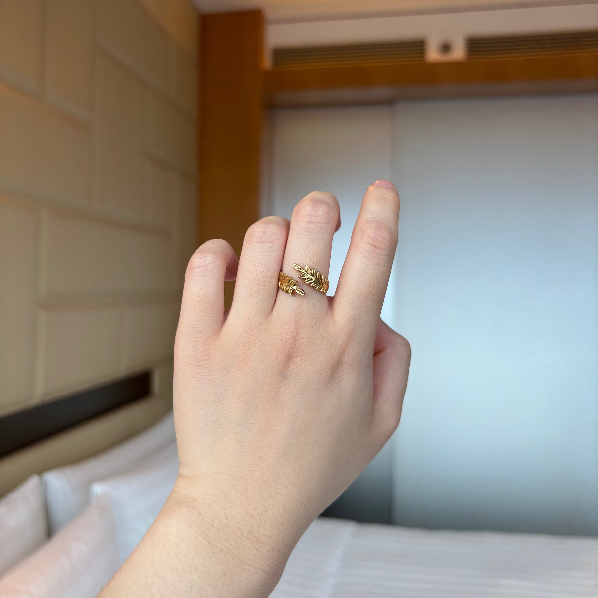 Hand wearing a gold ring with a blurred background